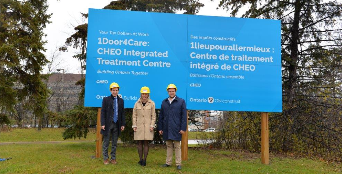 Group photo outside CHEO, in front of a sign reading "1Door4Care: CHEO integrated treatment centre"