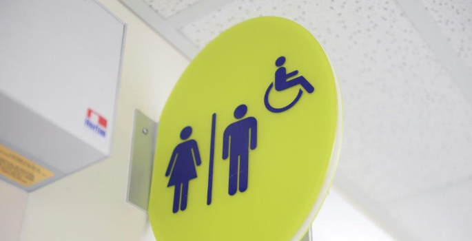 A bright green sign on the wall showing a designated gender-neutral and accessible washroom 