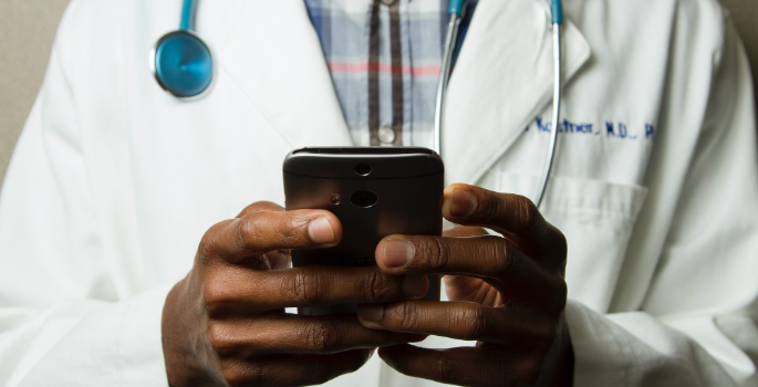 Photo of doctor in a lab coat, holding a cell phone