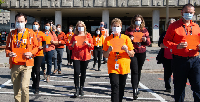 Photo of CHEO staff outside the main entrance, wearing orange shirts and walking towards the camera
