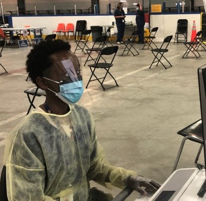 women dressed in PPE typing at a computer at the Brewer Assessment Centre.