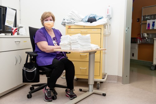 A CHEO volunteer wearing a mask and helping sort linens