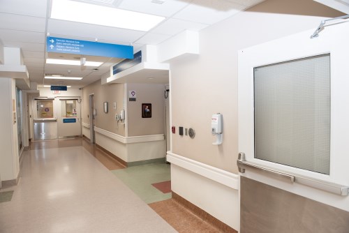 Photo of the NICU entrance, a hallway with white walls and blue wayfinding signs
