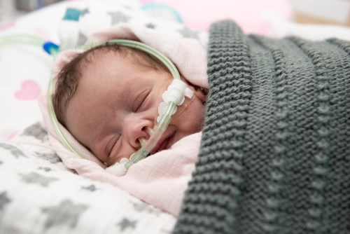 Baby in the NICU, resting under a green knit blanket