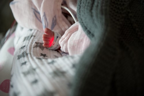 A glowing red light on a baby's foot, measuring their oxygen saturation