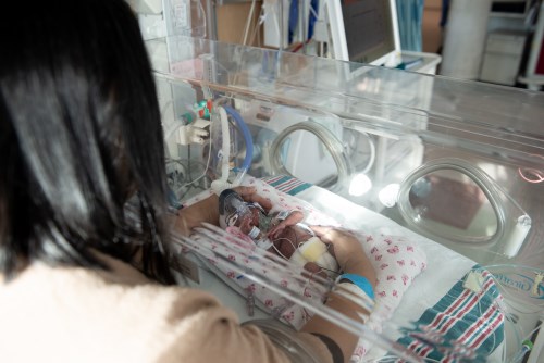 A parent providing modified kangaroo care by nesting or encircling their baby