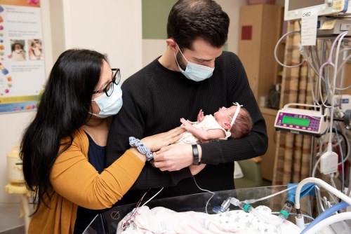 A mother and father holding their baby