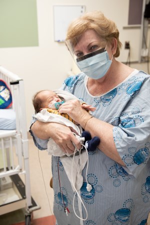 A CHEO volunteer wearing a mask and cuddling a baby