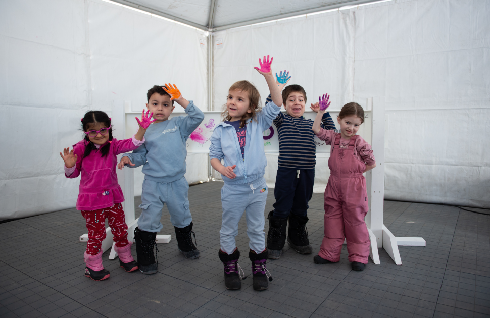 children hold painted hands in the air in front of white metal beam