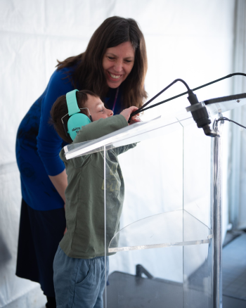 vera etches with boy grayson at podium with microphone