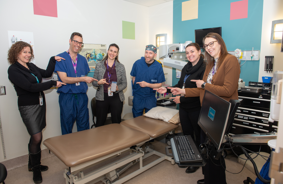 CHEO physician and leaders point to phone with AI scribe app featured