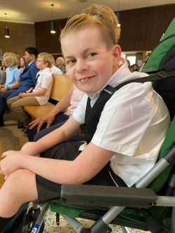 boy sits in wheelchair in room of people