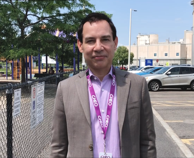 Alex Munter standing outside beside a playground and a parking lot