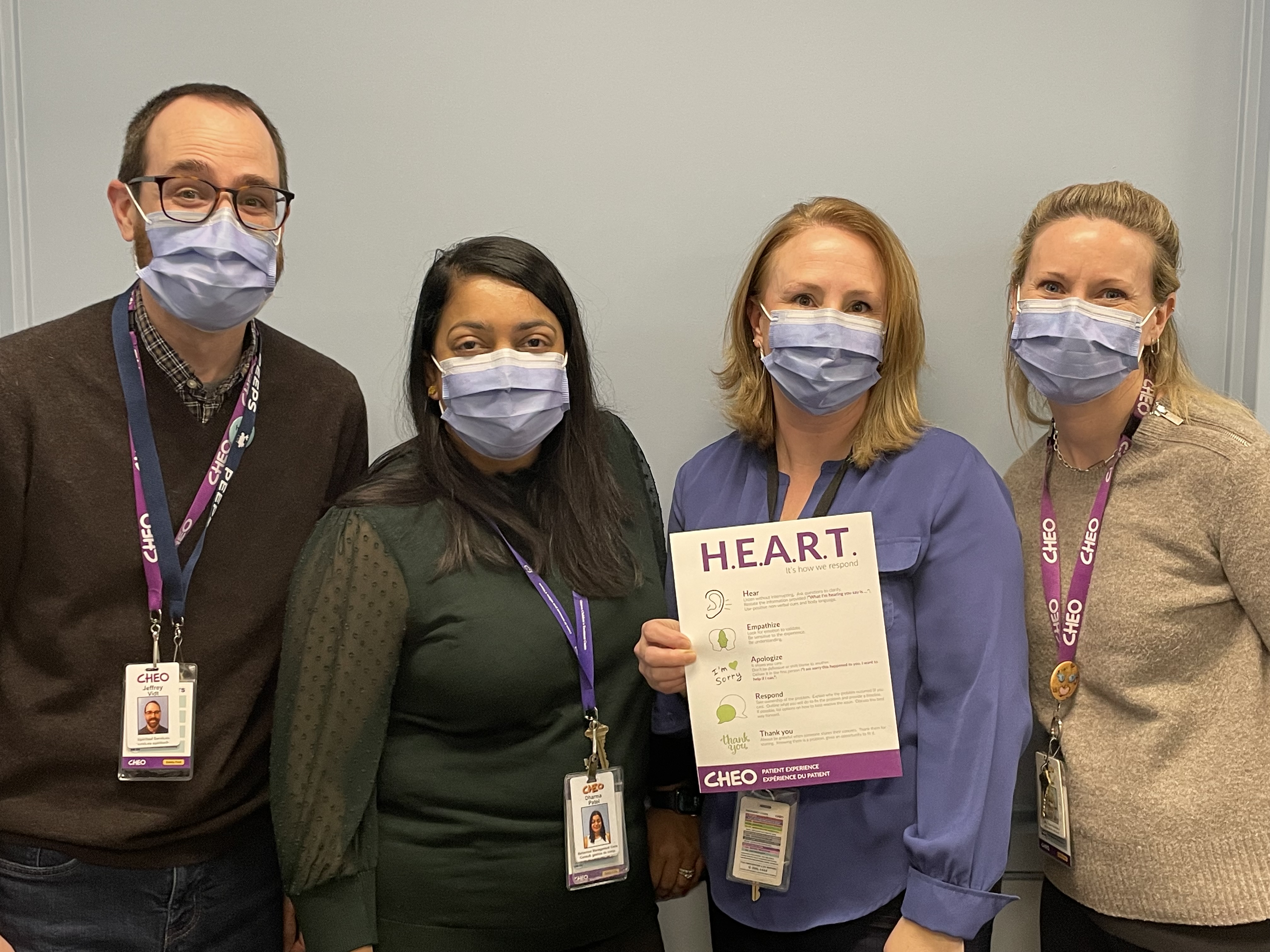 four members of patient experience team stand holding HEART steps on sign