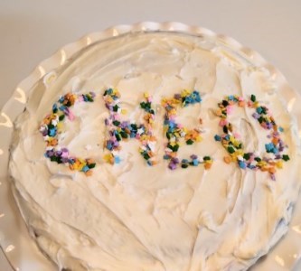 Birthday cake with 'CHEO' in sprinkles