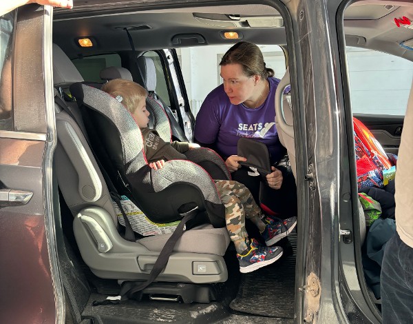 car seat technician talks to child in car seat