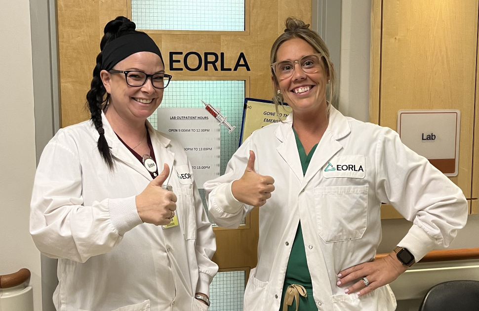 two lab techs gives thumbs up outside lab