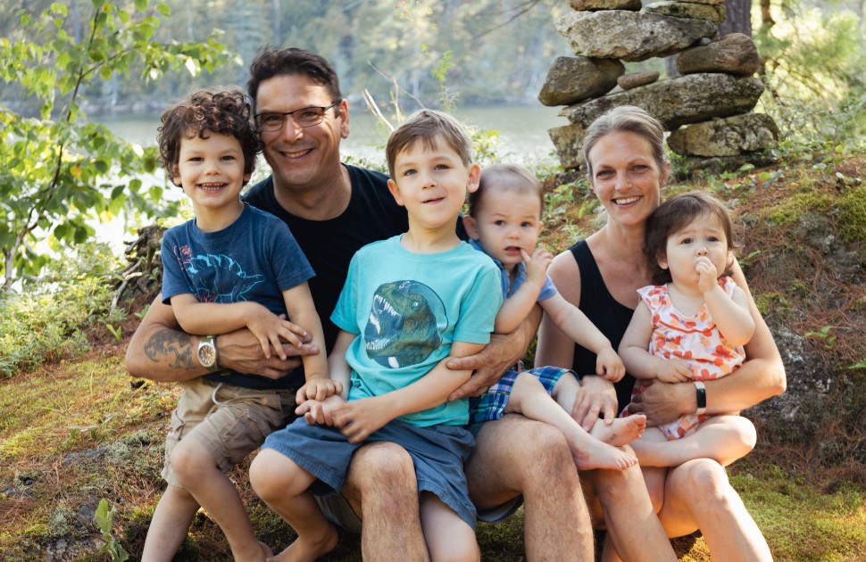 family of six sitting at a riverbank smiling at camera