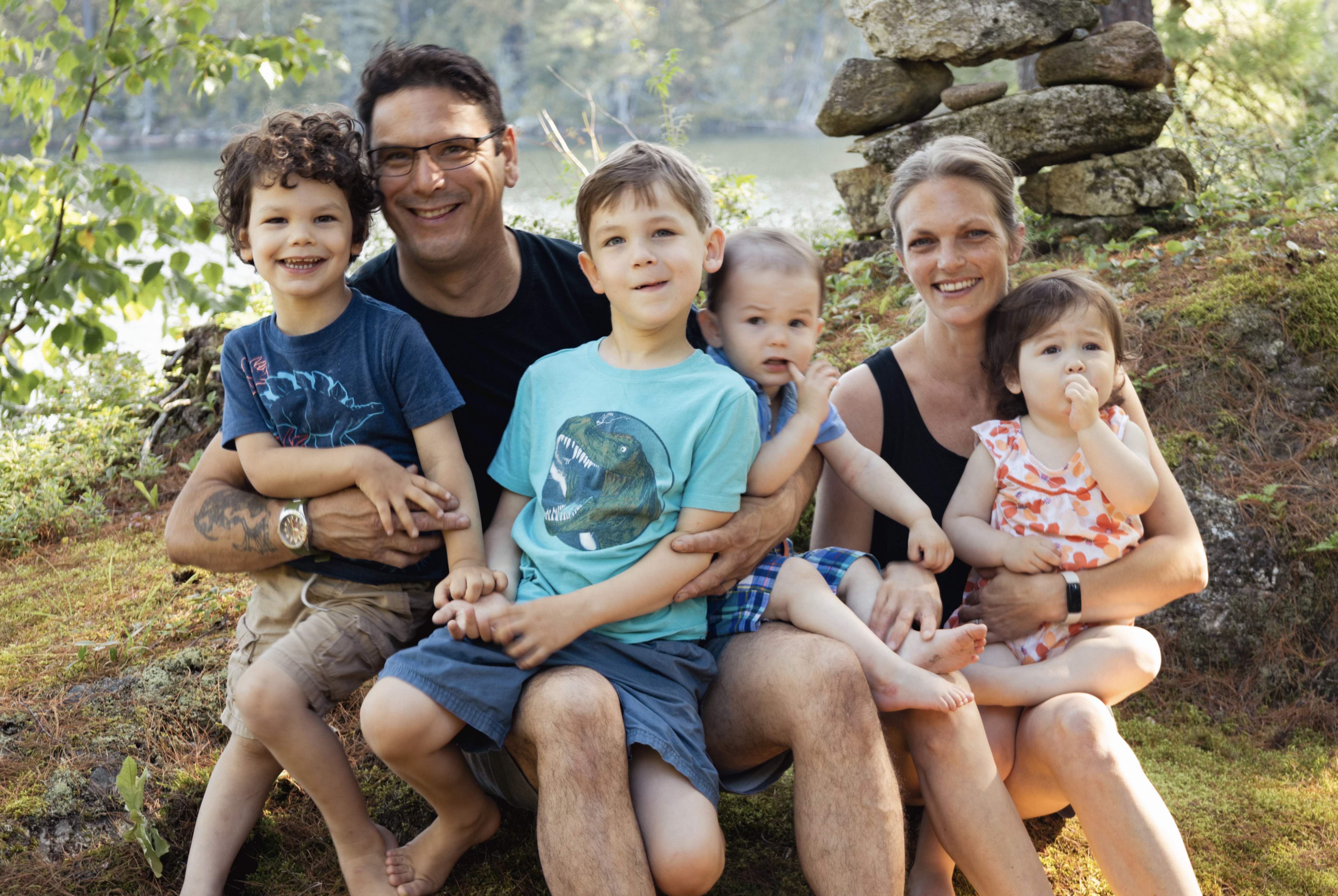 family of six sitting at a riverbank smiling at camera