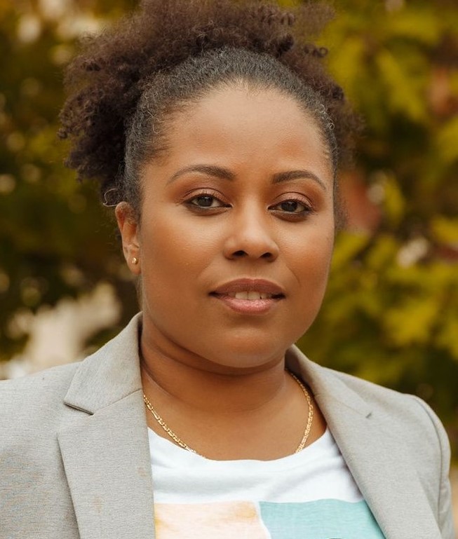 Headshot of Tanya in a grey blazer, smiling at the camera