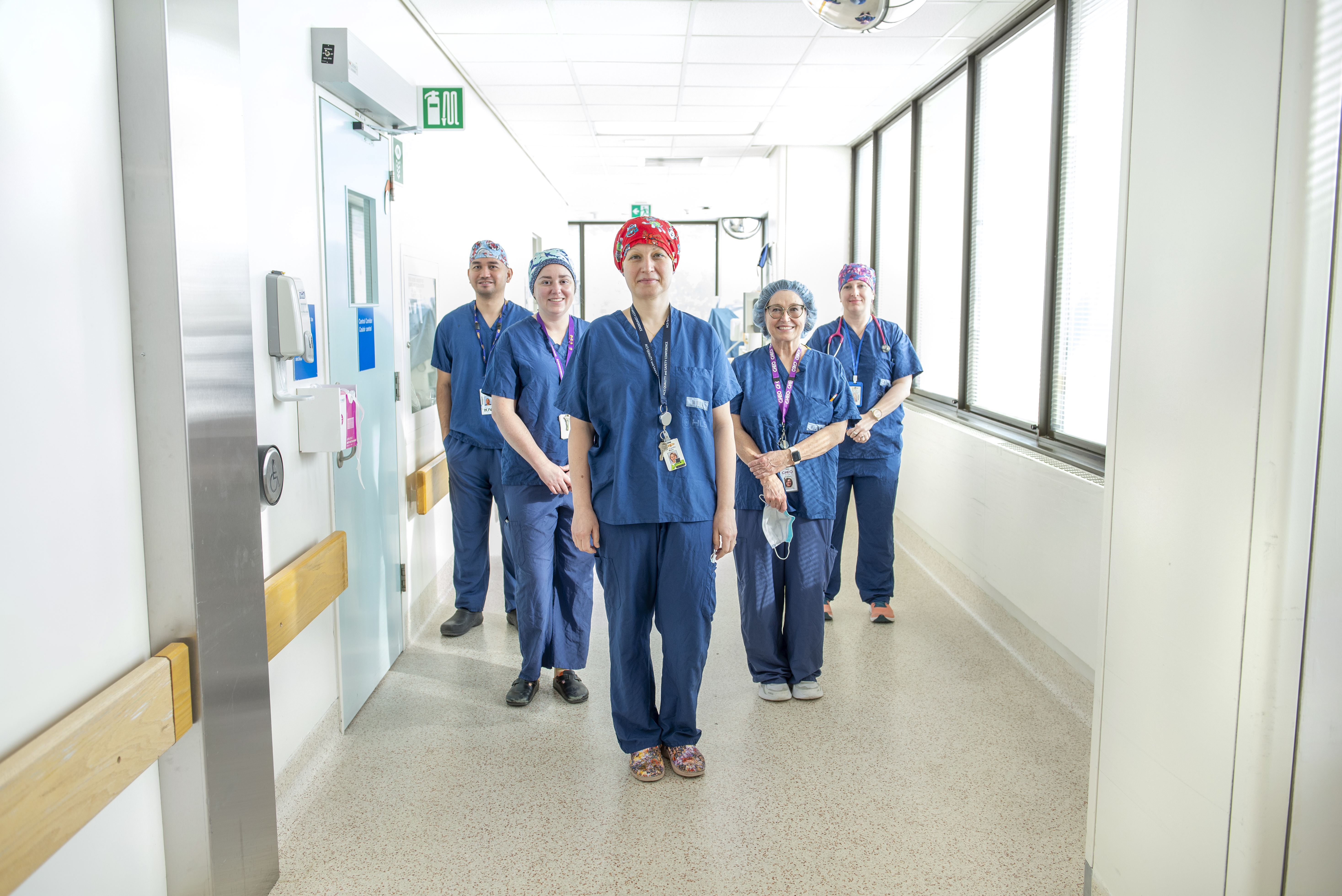 doctors and nurses stand in well-lit hospital hallway posing for camera