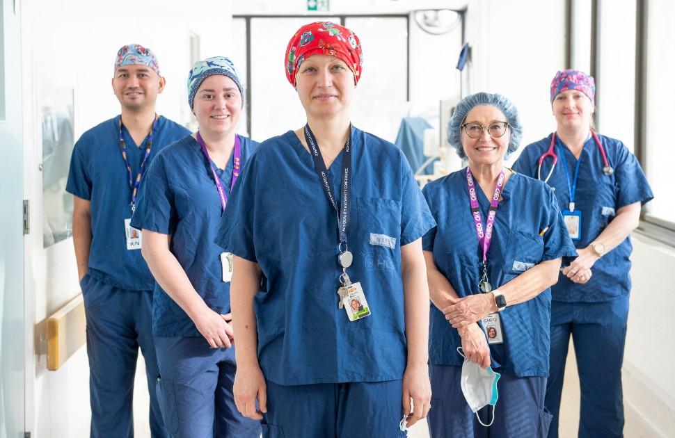 doctors and nurses stand in well-lit hospital hallway posing for camera