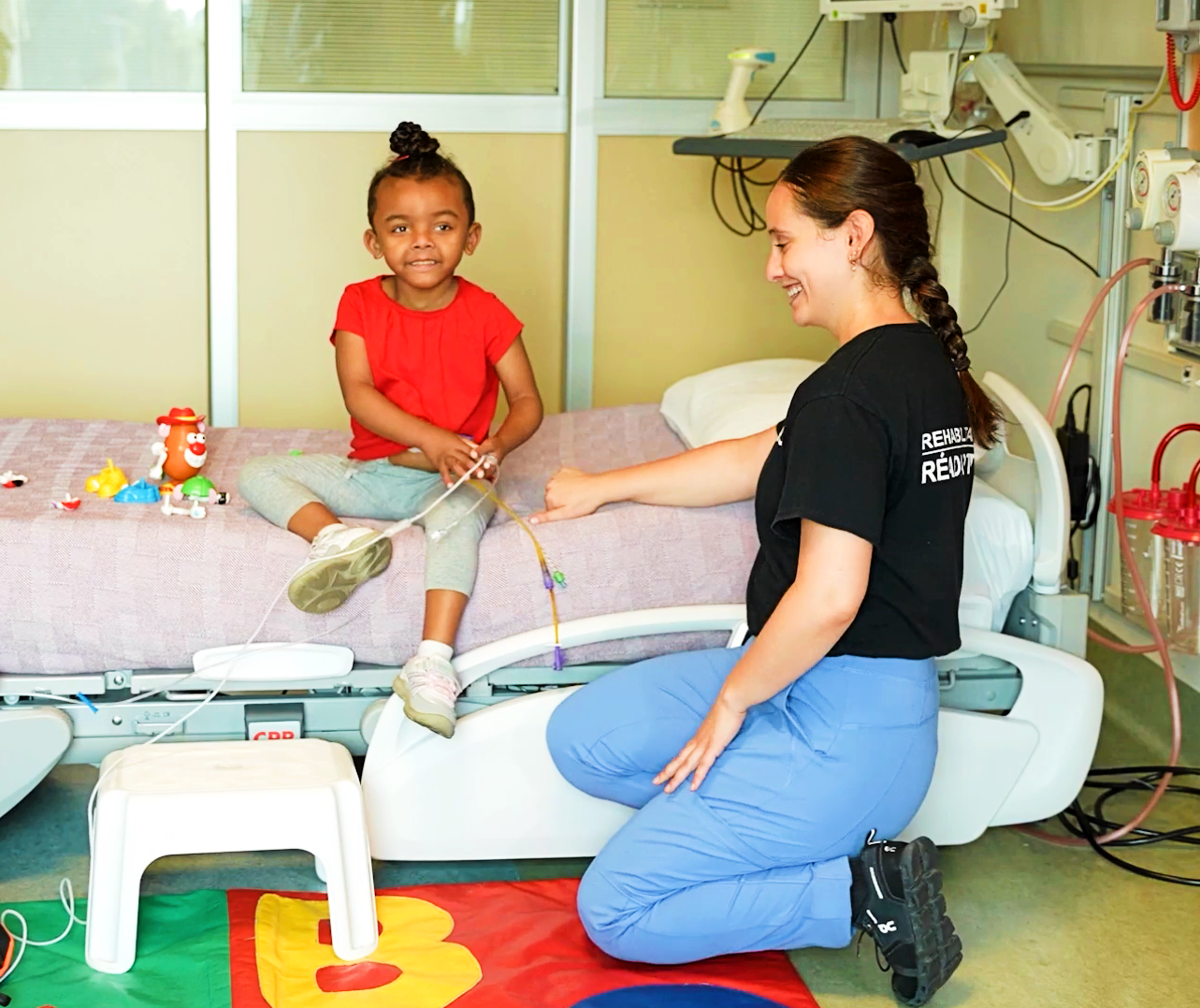 young girl and physiotherapist work on simple exercises on hospital bed