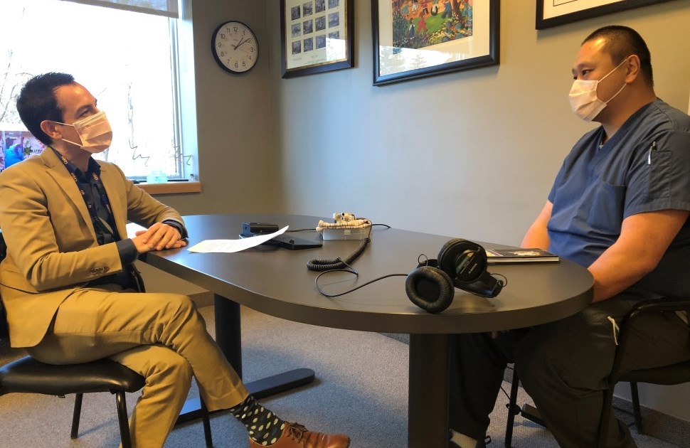 Alex Munter and Jackson Wu sitting at a table, wearing face masks with a microphone between them.