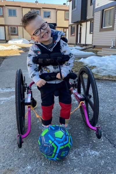 Malakai plays with a soccer ball while in his walker