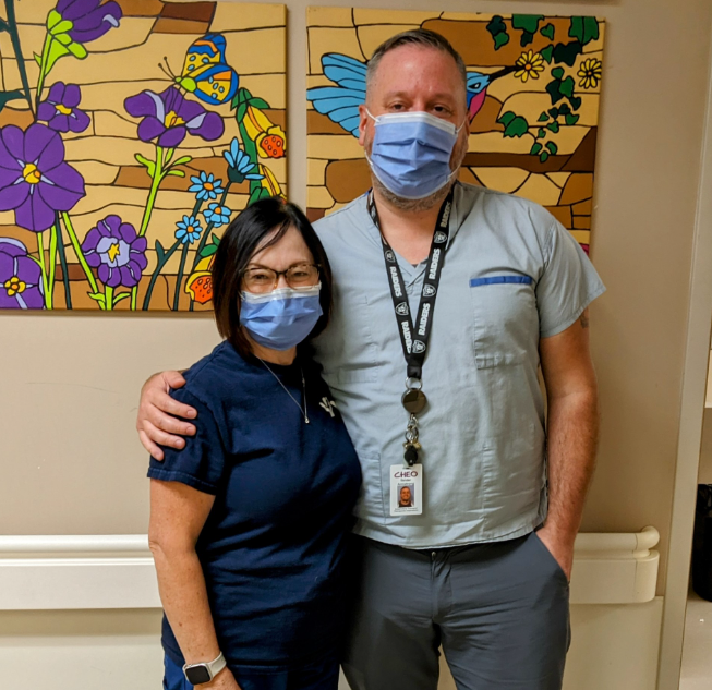 Maureen(left) and Strider (right) pose for a photo. They both wear masks.