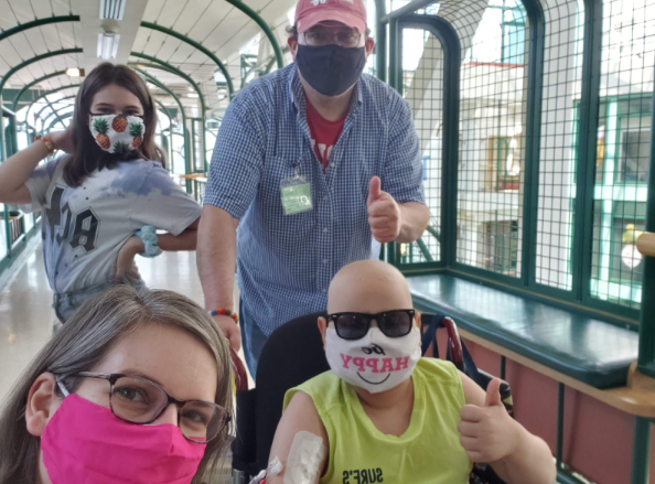 Ollie, Abby, Dawn, and Mario exiting SickKids Hospital. Ollie gives a thumbs up.