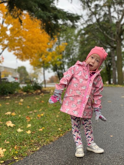 Payton in a pink raincoat and hat, smiling at the camera