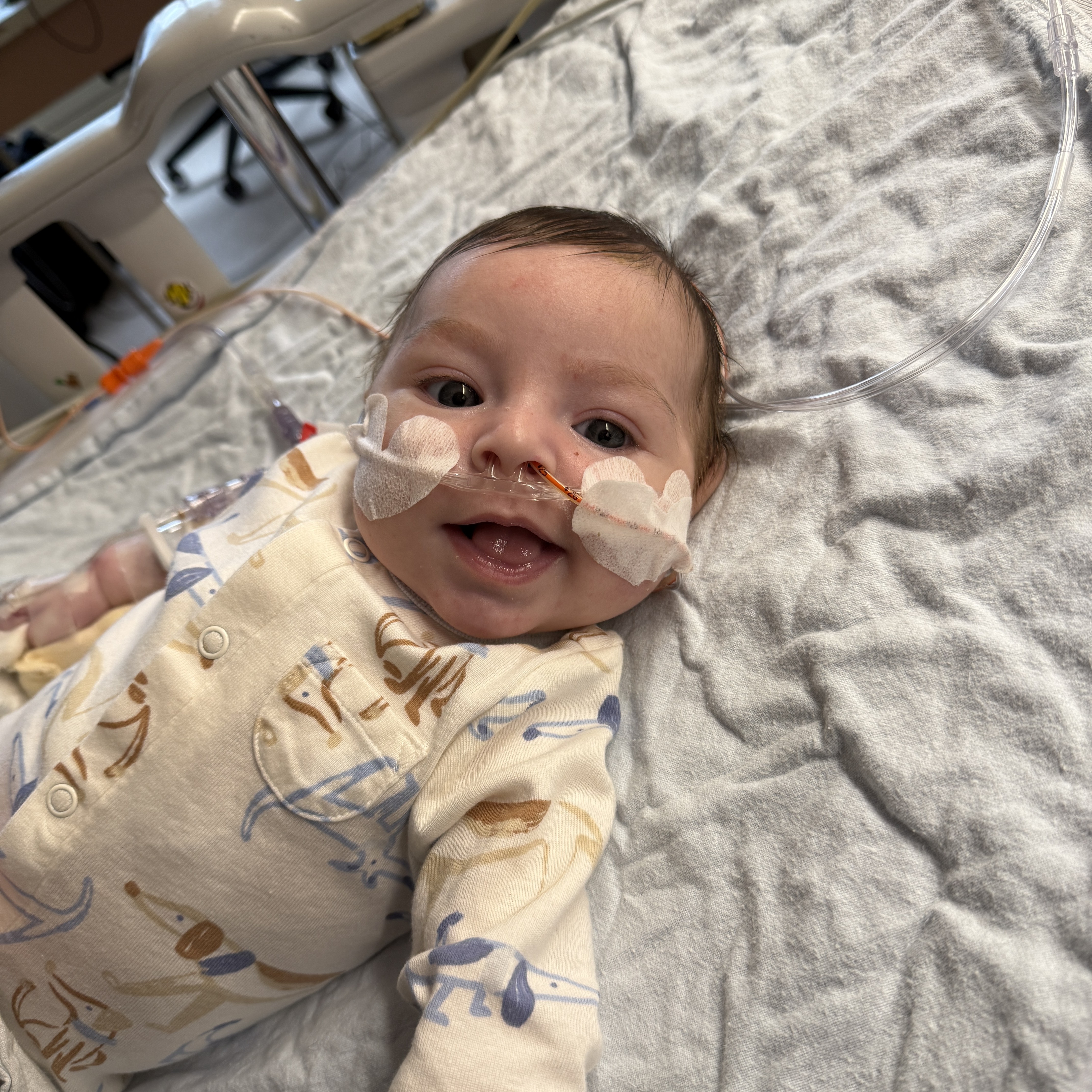baby smiling in hospital bed with tube in nose