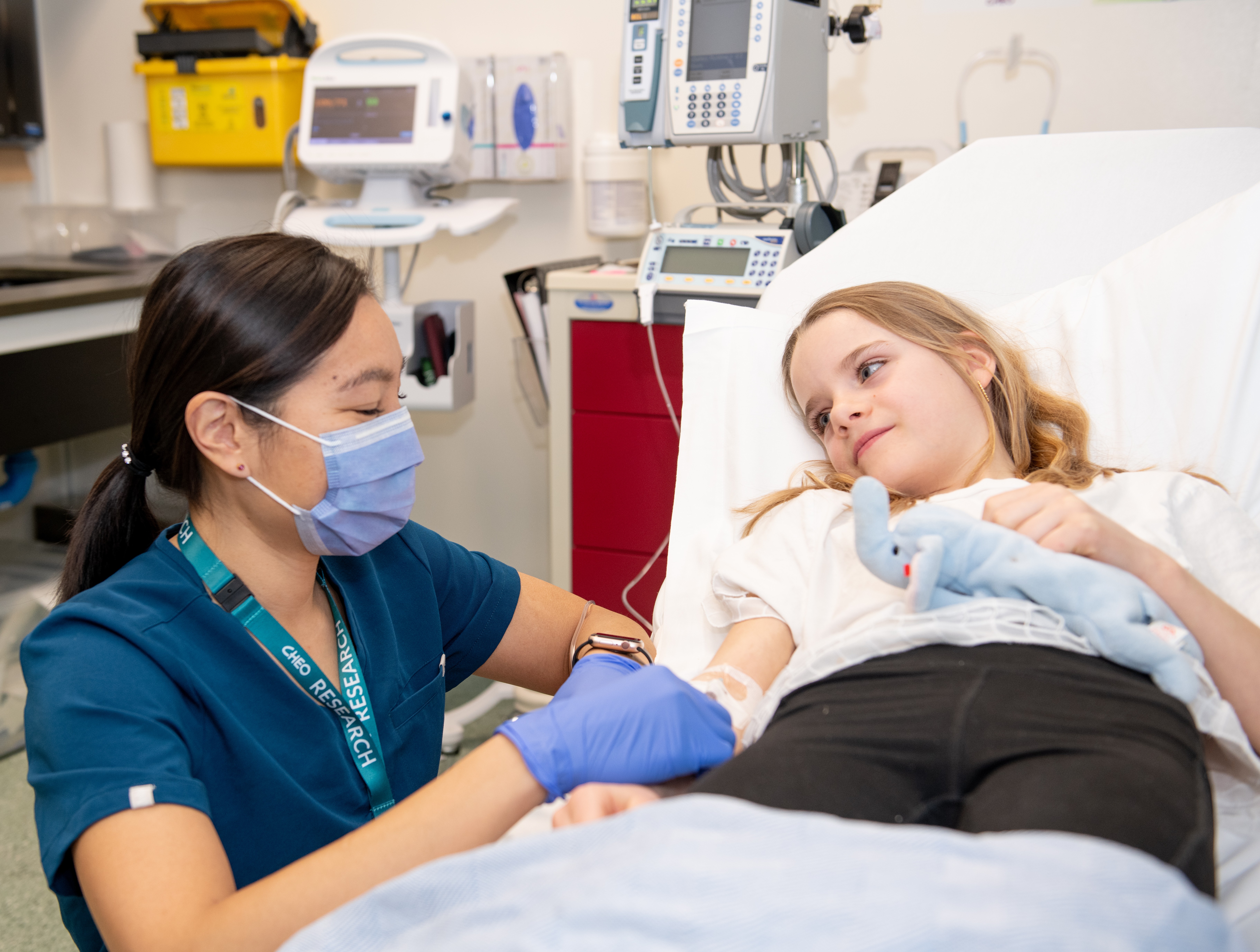 clinician kneels down at bedside of child patient