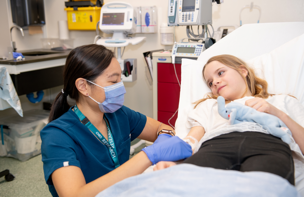 clinician kneels down at bedside of child patient