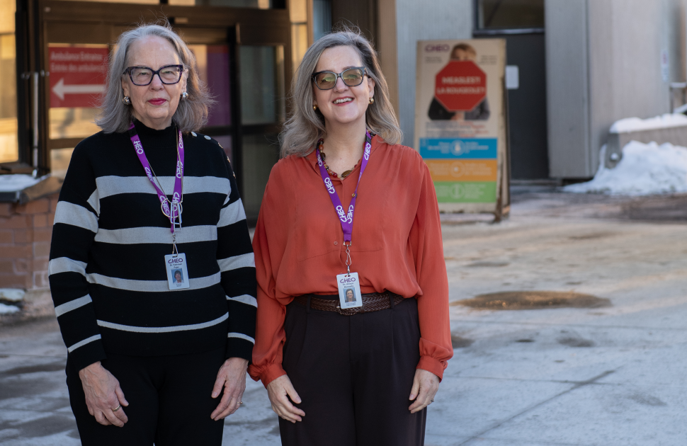 two female researchers stand outside CHEO ED in winter without coats