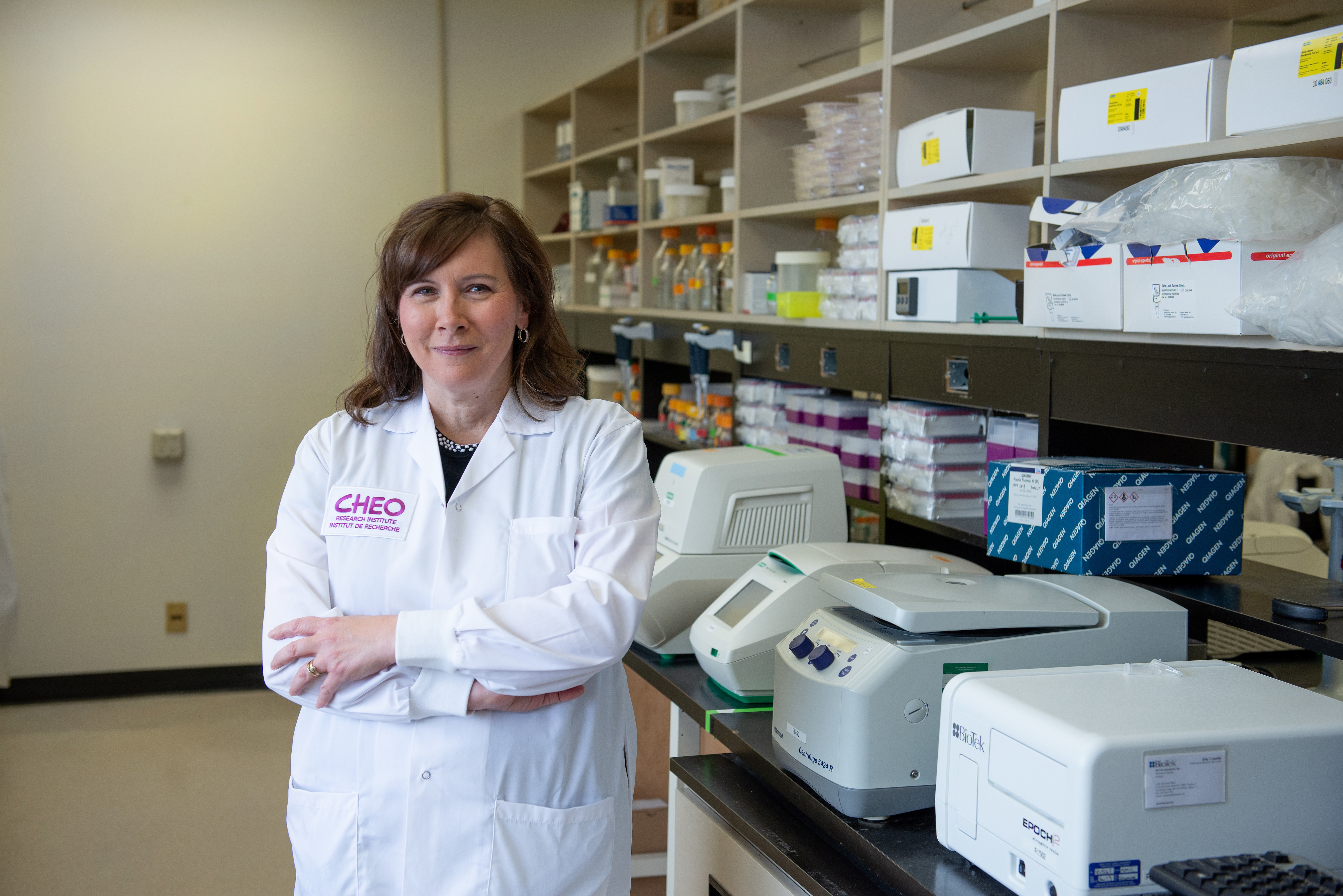 cheo researcher smiles and crosses her arms looking at camera while in lab