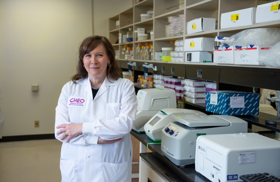 cheo researcher smiles and crosses her arms looking at camera while in lab