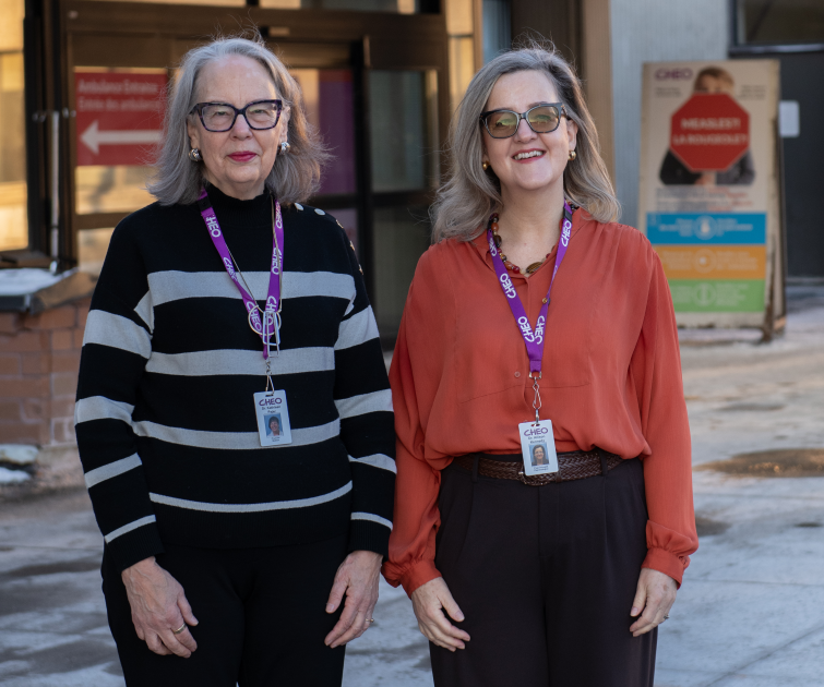 two female researchers stand outside CHEO ED in winter without coats