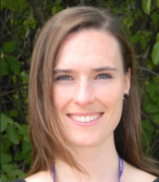 Photo of Catherine Dulude, standing against a background of trees, smiling at the camera