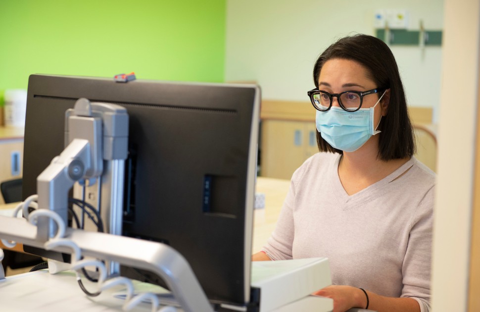 Woman wearing a face mask, sitting in front of a computer