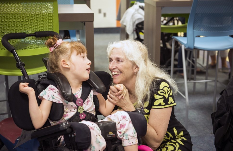 Girl in wheelchair holding hand with CHEO staff member 