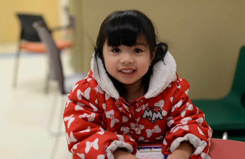 A young girl in a winter coat, smiling at the camera