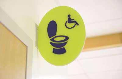 Bright green accessible washroom sign next to the washroom door