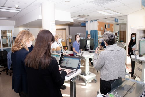 A group of CHEO staff gathered, wearing masks, for daily rounds.